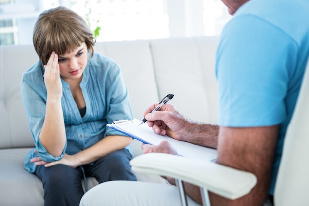 Woman looking at doctor writing on clipboard 