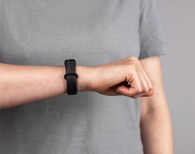 Woman looking at fitness tracker for checking physical activity\
results female with band at wrist for walking steps running\
distance heart rate or sleep patterns monitoring