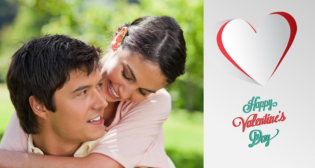 Woman looking at her friend while he is carrying her  against cute valentines message