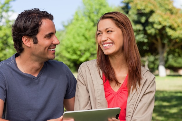 Woman looking at her friend while she is holding a tablet