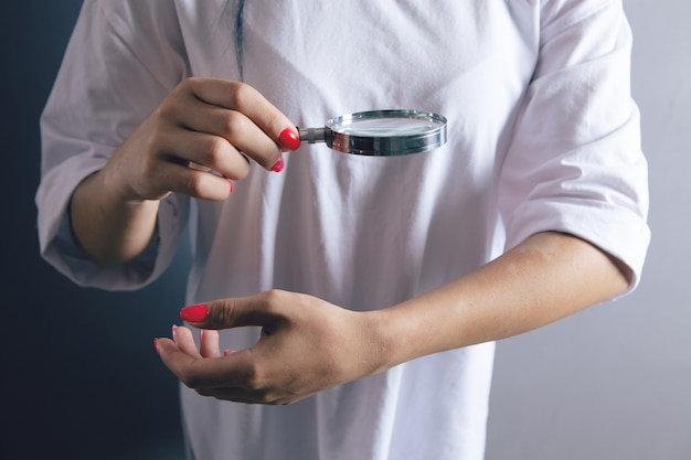 Woman looking at her hand with a magnifying glass