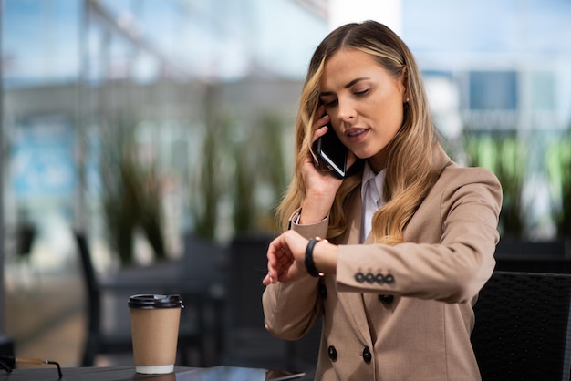 Woman looking at her watch while talking on the phone