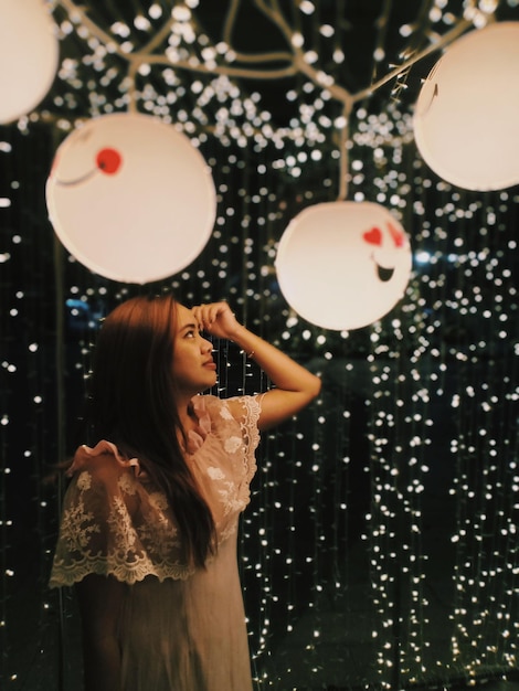 Photo woman looking illuminated decoration at night