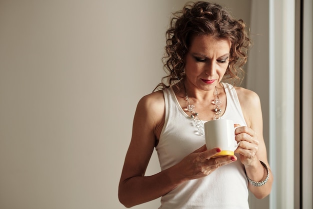 Donna che guarda all'interno della tazza di caffè