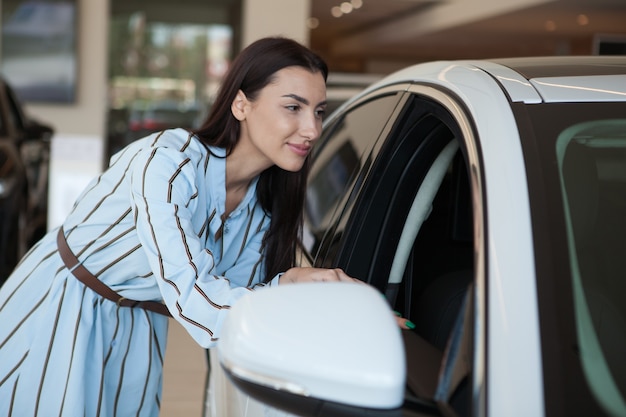 Woman looking inside new automobile at car dealership