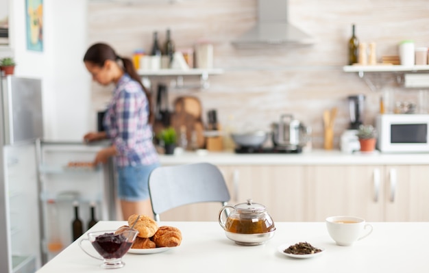 Woman looking into refrigerator for food to prepare breakfast in kitchen