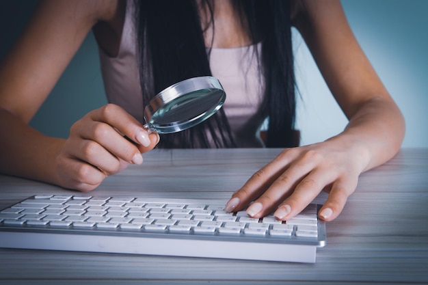 Woman looking at the keyboard with a magnifying glass