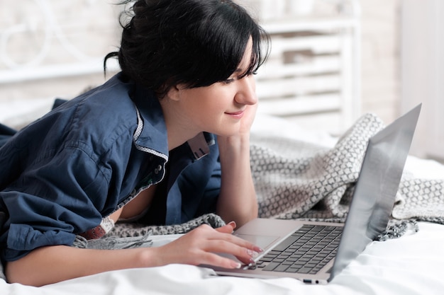 Woman looking at laptop lying in bed