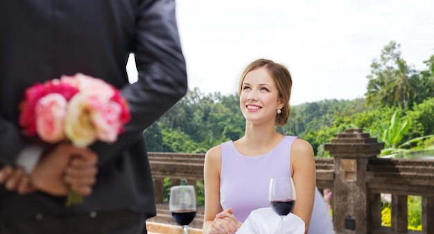 Foto donna che guarda l'uomo con i fiori al ristorante