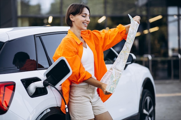 Donna che guarda la mappa durante la ricarica dell'auto elettrica