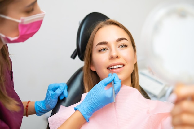 Woman looking to mirror after teeth treatment in modern clinic