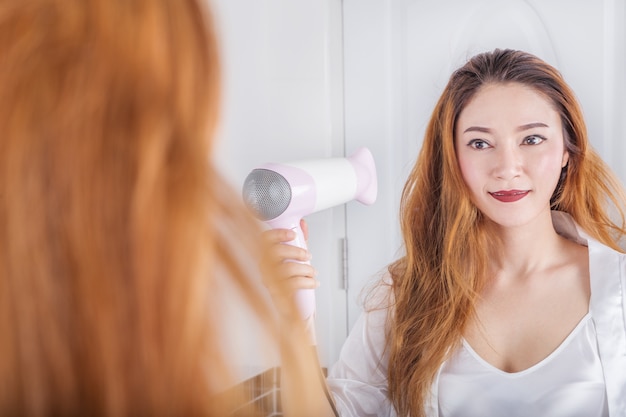 woman looking in the mirror drying her hair