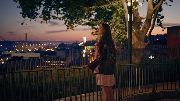 Woman looking night cityscape standing at railings girl enjoying twilight sky