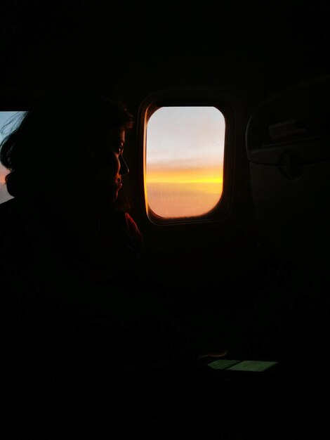 Photo woman looking out through window while traveling in airplane sunset