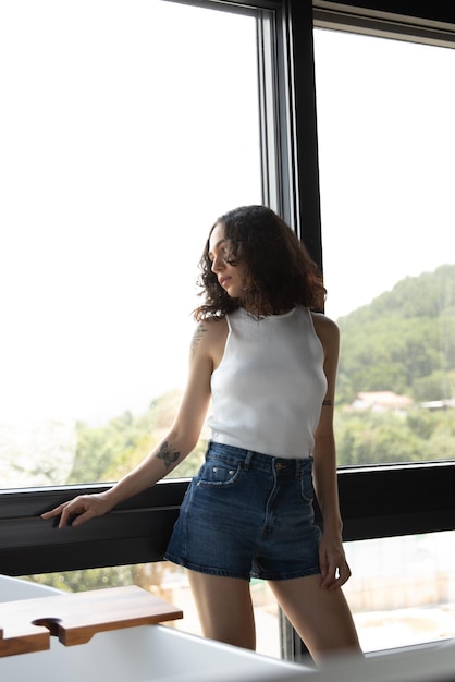 Photo woman looking out window, beautiful woman in her bedroom, tattoo woman beautiful woman