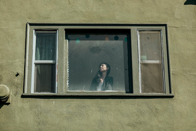 Woman looking out the window of her downtown LA apartment during the covid-19 pandemic