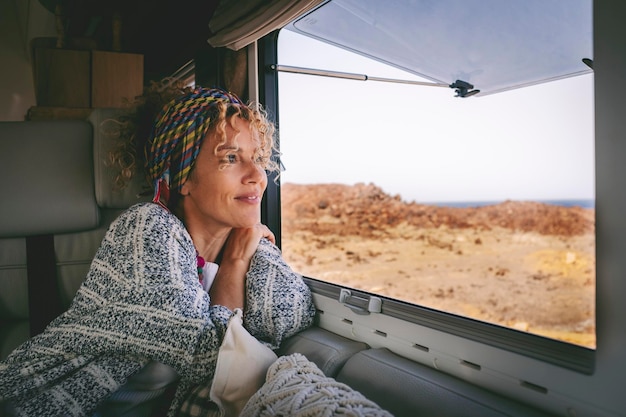 A woman looking out the window of a van with a scarf on her head.