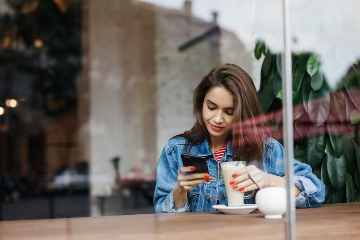 コーヒーショップで携帯電話を探している女性