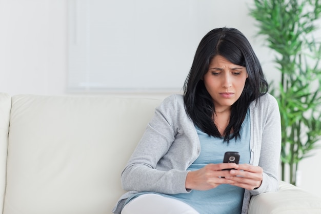 Woman looking at a phone on a couch