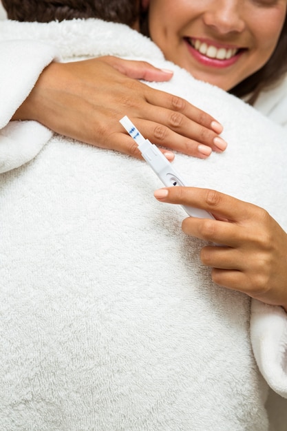 Woman looking at pregnancy test while embracing a man