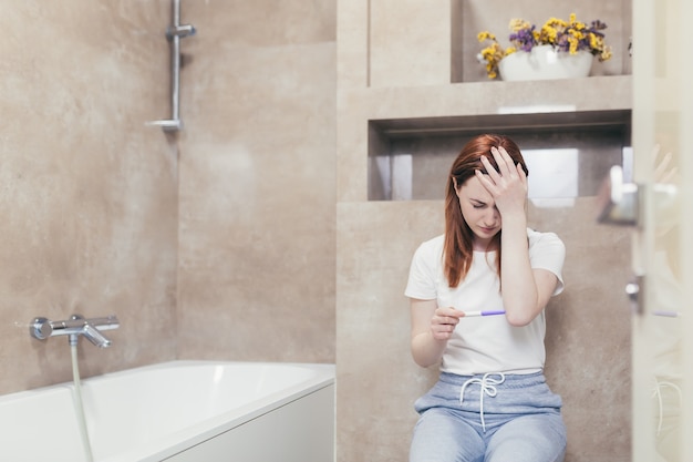 woman looking at a quick positive or negative result pregnancy test