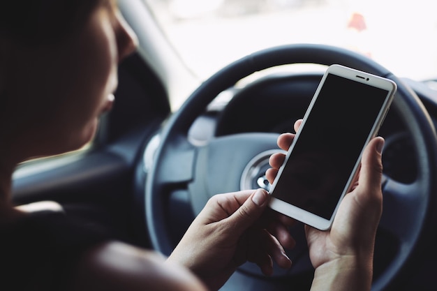 Woman looking at the screen of the smartphone in the car