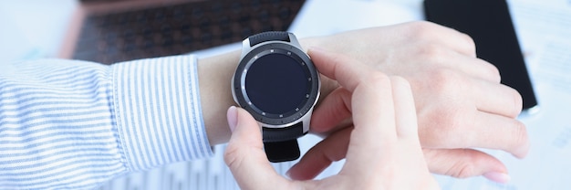 Woman looking at smart watch at workplace closeup deadline concept