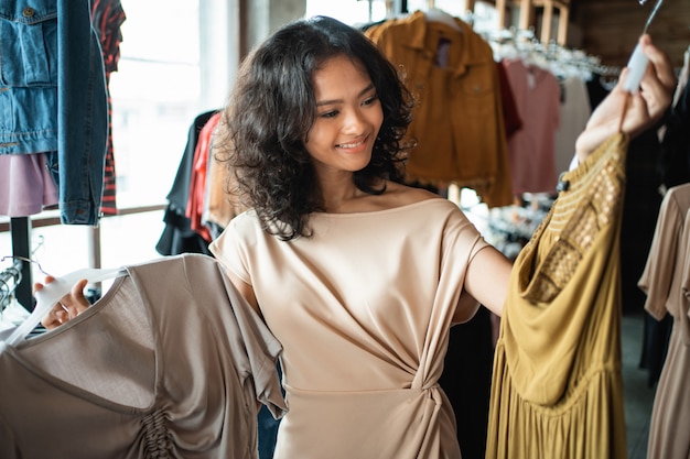 ファッション店でいくつかの服を探している女性