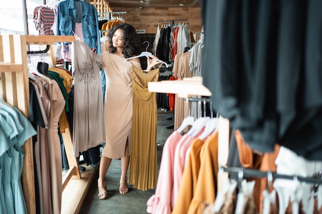 ファッション店でいくつかの服を探している女性