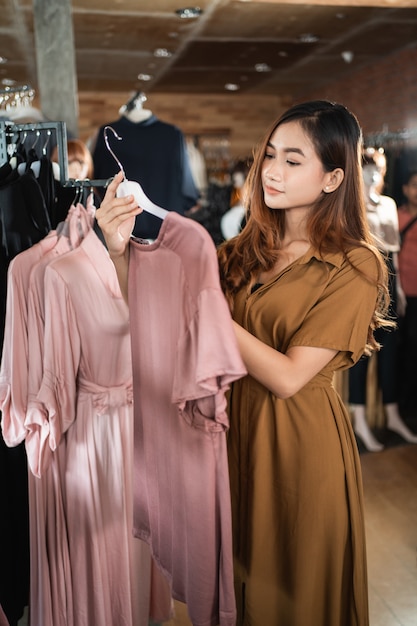 Женщина смотрит на одежду в магазине модной одежды