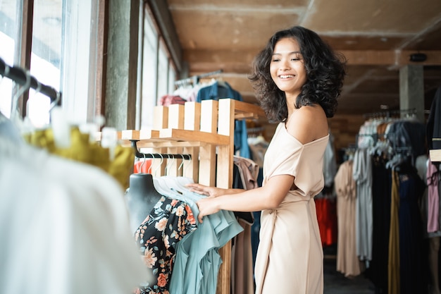 ファッション店でいくつかの服を探している女性