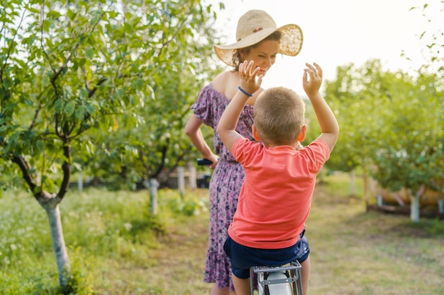 Foto donna che guarda il figlio seduto su una bicicletta