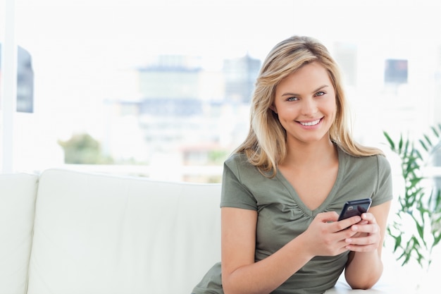 Woman looking straight ahead and smiling as she uses her phone