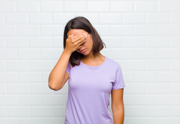 Woman looking stressed, ashamed or upset, with a headache, covering face with hand