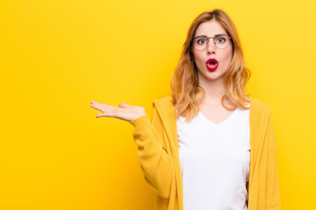 woman looking surprised and shocked, with jaw dropped holding an object with an open hand on the side