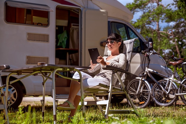 Photo woman looking at the tablet near the camping . caravan car vacation. family vacation travel, holiday trip in motorhome rv. wi-fi connection information communication technology.