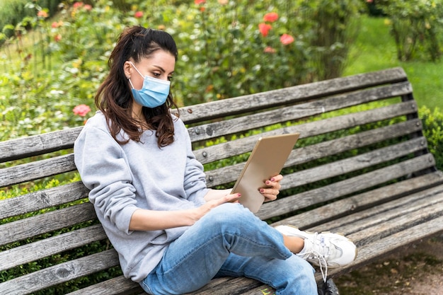 Donna che guarda un tablet mentre indossa la maschera medica