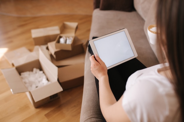 Woman looking at a tablet with empty boxes behind