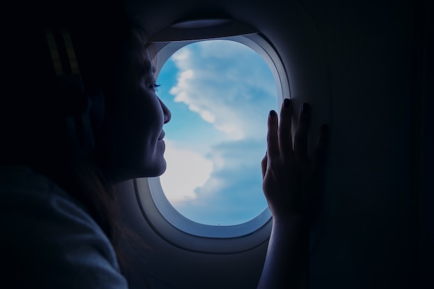 woman looking through an airplane window 