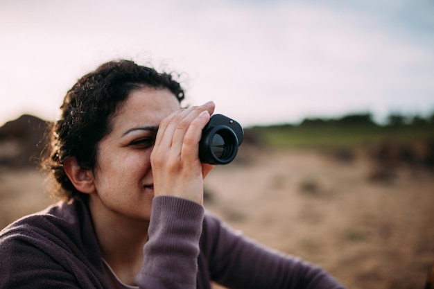 写真 フィールドで双眼鏡を通して見ている女性