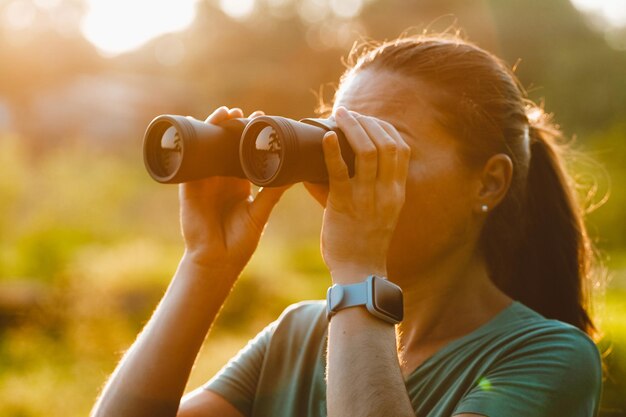 Photo woman looking through binoculars at the nature of the pantanal in brazil beautiful sunset view of the lake watching birds and other wild animals