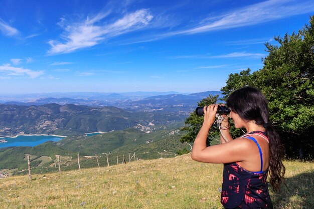 Photo woman looking through binoculars while standing on land