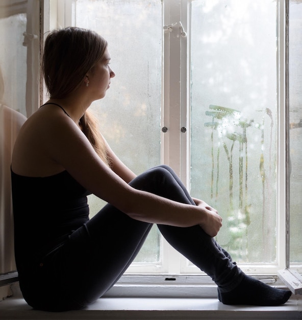 woman looking through window during monsoon