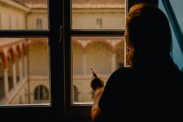 woman looking trough window shadows