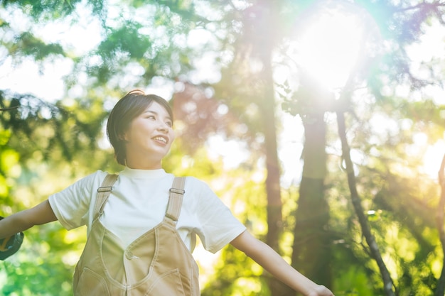 晴れた日に森の木々を見上げる女性