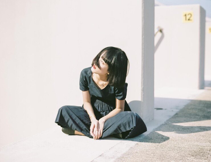 Photo 晴れた日に壁に寄りかかって座っている女性
