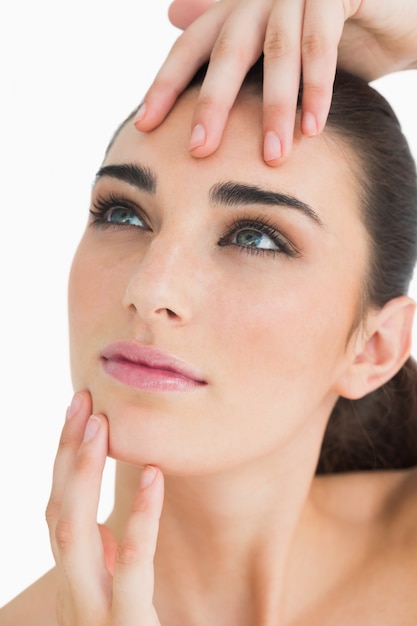 Woman looking up while touching her face