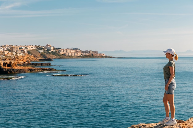 A woman looks at the city by the sea travel and active lifestyle concept