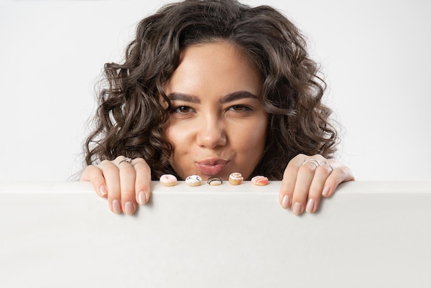 A woman looks at miniature sweet donuts with regret and envy wanting to eat them