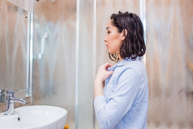 A woman looks in the mirror after a shower, dresses, applies makeup.